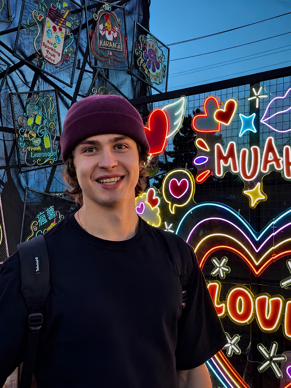 Vladislav Kovalenko, smiling at night in front of neon signs